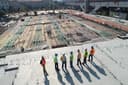Group of construction workers stand on a concrete deck overlooking an active site with rebar.