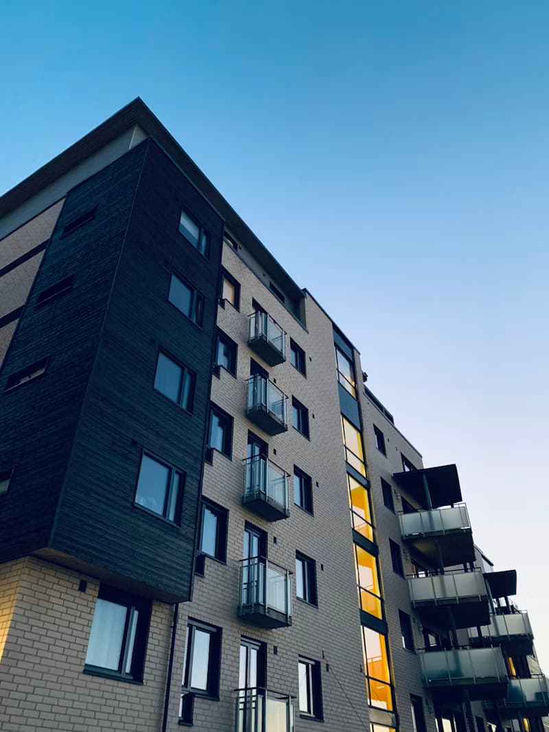 Modern residential building with contrasting dark and light facades, balconies, and reflecting windows.